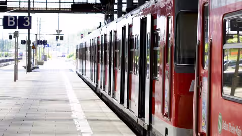 Ein roter Regional- oder S-Bahn-Zug steht am Bahnsteig eines Bahnhofs.