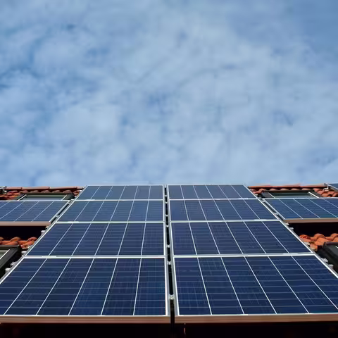 Foto. Blick aus der Froschperspektive auf die blauen Solarmodule auf dem Schrägdach eines Einfamilienhauses