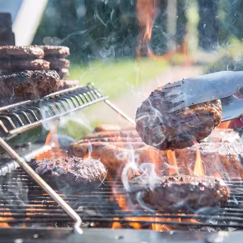 Foto: ein Holzkohlegrill mit Pattys für Hamburger und anderem Grillgut