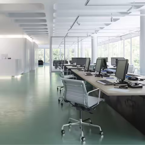 Foto: ein leeres Großraumbüro mit rund einem Dutzend PC-Arbeitsplätzen und großer Fensterfront