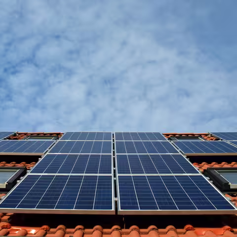 Foto: Blick aus der Froschperspektive auf eine Photovoltaikanlage auf dem Schrägdach eines Wohnhauses