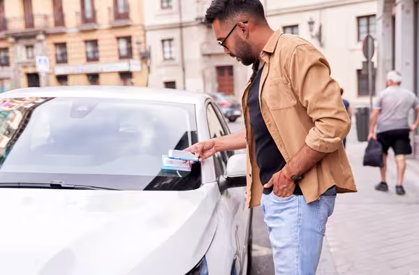 Eine Person scannt per Smartphone den QR-Code an einem Carsharing-Auto, um es zu aktivieren.