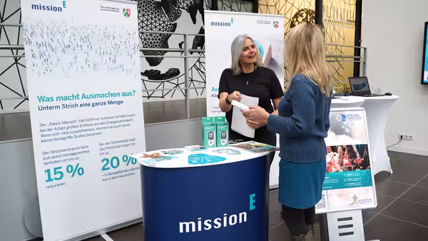 Foto: der Infostand des Landeskriminalamtes NRW mit einer Theke, zwei Roll-ups der mission E und einem Aufsteller