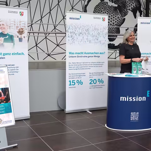Foto: der Infostand des Landeskriminalamtes NRW mit einer Theke, mehreren Roll-ups der mission E und zwei Aufstellern zu den Energiewochen 2025