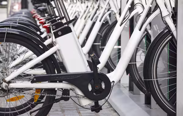 Mehrere weiße Leihfahrräder stehen dicht nebeneinander in einer Fahrradstation.