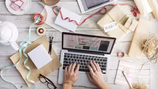 Foto: Blick von oben auf einen Tisch mit verschiedenen Bastelutensilien und einem Notebook.