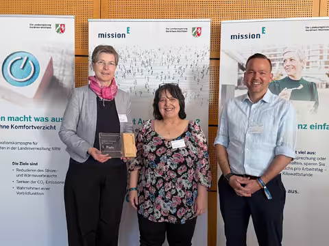 Foto: Grit Werth, eine Frau mit kurzem grauem Haar und randloser Brille, hält die Auszeichnung für die Staatliche Zentralstelle für Fernunterricht in die Kamera; neben ihr stehen freudestrahlend Gabi Heimstadt und Torsten Lau, ebenfalls von der ZFU.