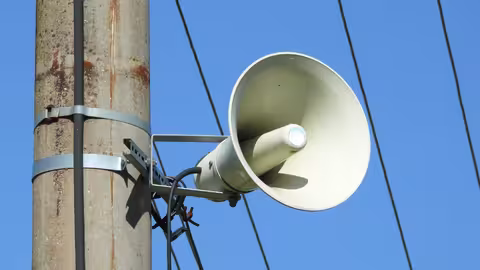 Foto: ein Megaphon, das an einem Strommast hängt