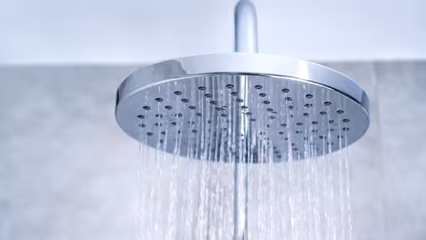 Moderne, runde Duschkopfbrause lässt Wasser in feinen Strahlen nach unten regnen.