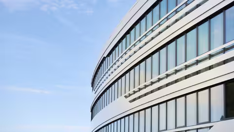 Foto: Ausschnitt der gewölbten Außenfassade eines modernen Bürogebäudes mit großer Fensterfront