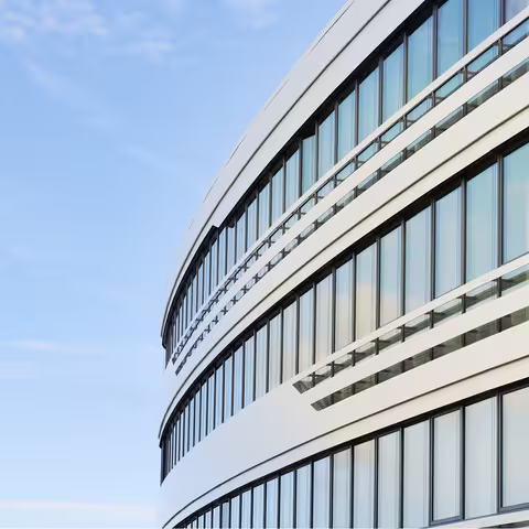 Foto: Ausschnitt der gewölbten Außenfassade eines modernen Bürogebäudes mit großer Fensterfront