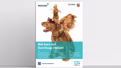 Das im folgenden Text beschriebene Poster “Lüftungscheck” steht vor einer grauen Wand.