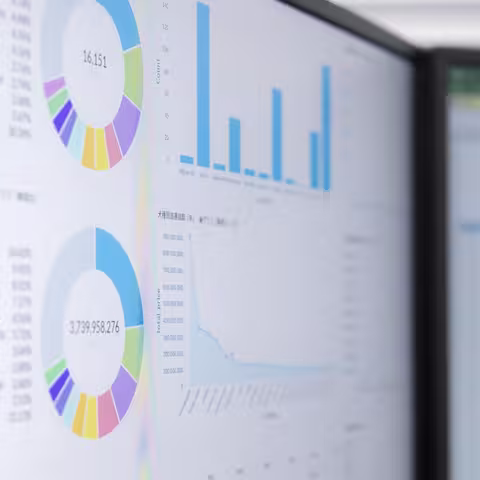 Foto: Nahaufnahme von zwei sehr hell eingestellten Monitoren mit Diagrammen und Tabellen