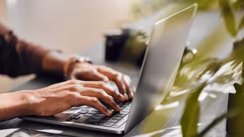 Foto: Ein Mann mit dunkler Hautfarbe schreibt auf seinem Notebook.