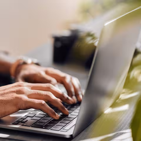 Foto: Ein Mann mit dunkler Hautfarbe schreibt auf seinem Notebook.