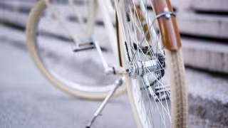 Nahaufnahme eines Fahrrads, bei dem hauptsächlich das Vorderrad, die Speichen und der braune Schutzblechbereich zu sehen sind.