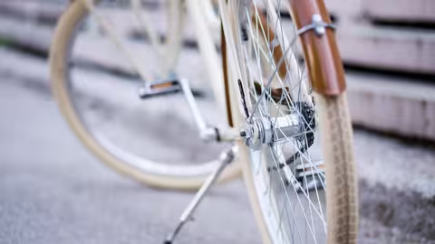 Nahaufnahme eines Fahrrads, bei dem hauptsächlich das Vorderrad, die Speichen und der braune Schutzblechbereich zu sehen sind.