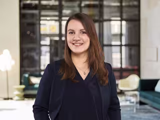 Judith Geusen hat langes, braunes Haar und trägt einen dunkelblauen Blazer.