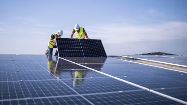 Foto: zwei Ingenieure, die Sonnenkollektoren auf einem Dach installieren