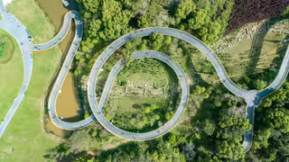 Foto aus der Vogelperspektive: grüner Wald im Park mit einem kreisförmig gewundenen Bergwanderweg