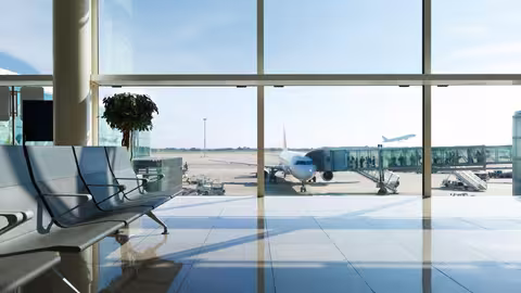 Foto: Blick aus einem leeren Sitzbereich eines Gates am Flughafen auf das Rollfeld mit einem Flugzeug in der Bildmitte