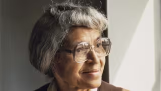 Foto: Portrait von Rosa Parks im hohen Alter - mit grauen, hochgesteckten Haaren und einer großen Brille.