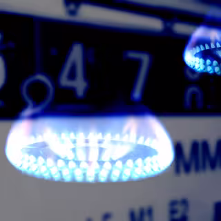 Foto: Montage einer kleinen blauen Gasflamme und eines Gaszählers.