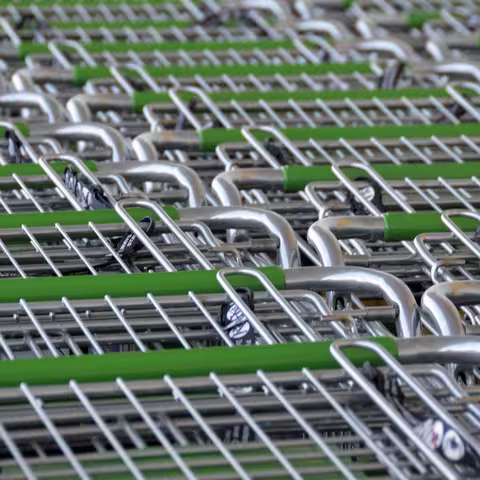 Foto: zwei Reihen von ineinandergeschobenen Einkaufswagen aus Augenhöhe von vorn fotografiert