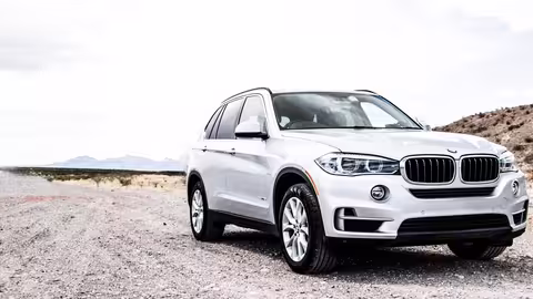 Silberner SUV steht auf einer staubigen Landstraße in einer offenen, bergigen Landschaft.
