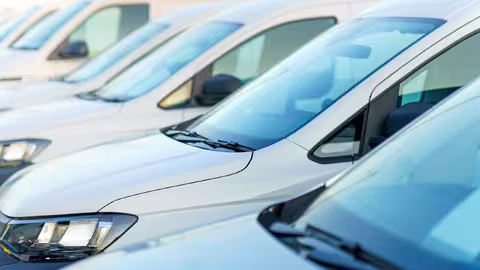 Foto: eine Reihe dicht nebeneinander stehender, blauer und weißer Gebrauchtwagen, fotografiert von links vorn