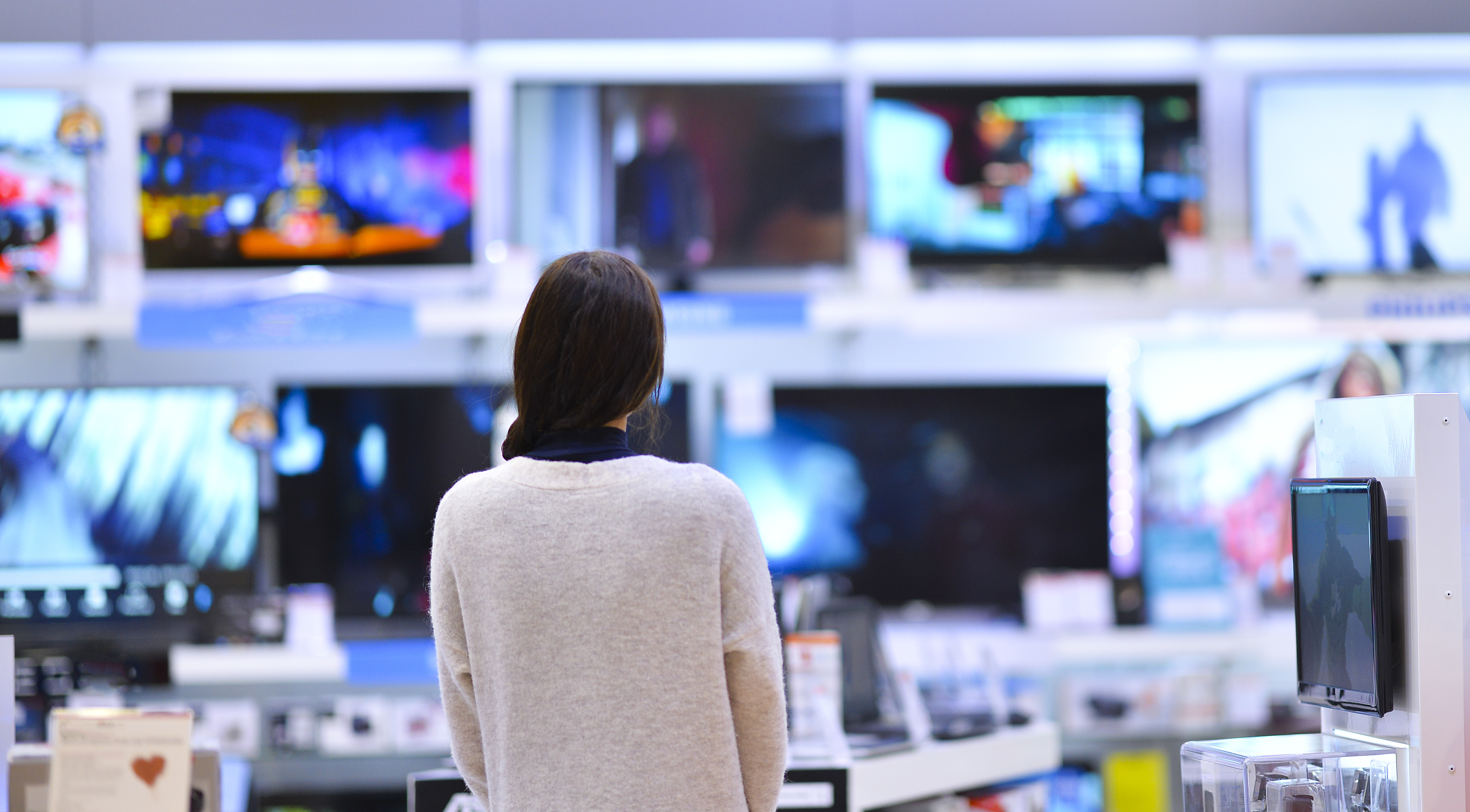Eine Frau vor vielen Fernsehern in einem Megastore