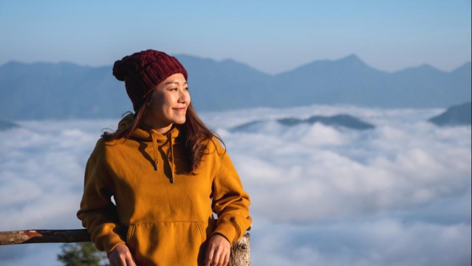 eine junge Frau in den Bergen mit einem Nebelmeer am Morgen