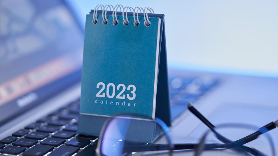 ein Jahreskalender 2023 und eine Brille auf der Tastatur eines Notebooks