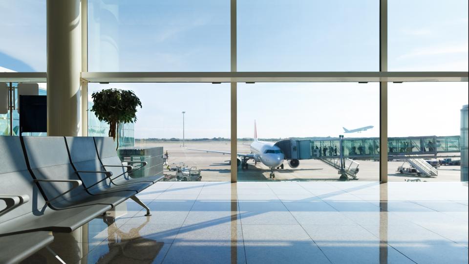ein Flughafen Wartebereich vor einer Fensterfront hinter der ein Flieger zusehen ist