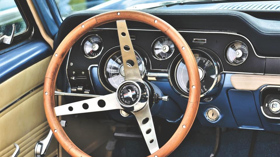 das Cockpit eines alten blauen Ford Mustang mit Holzlenkrad