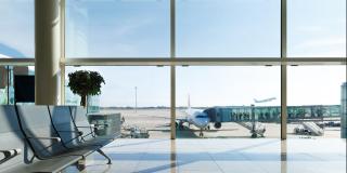 ein Flughafen Wartebereich vor einer Fensterfront hinter der ein Flieger zusehen ist
