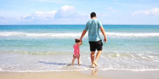 ein Vater mit seiner kleinen Tochter an der Hand am Strand