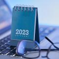 ein Jahreskalender 2023 und eine Brille auf der Tastatur eines Notebooks